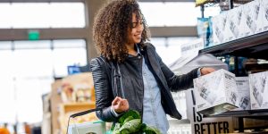 Woman taking box off the shelf in grocery store - suburbs or city