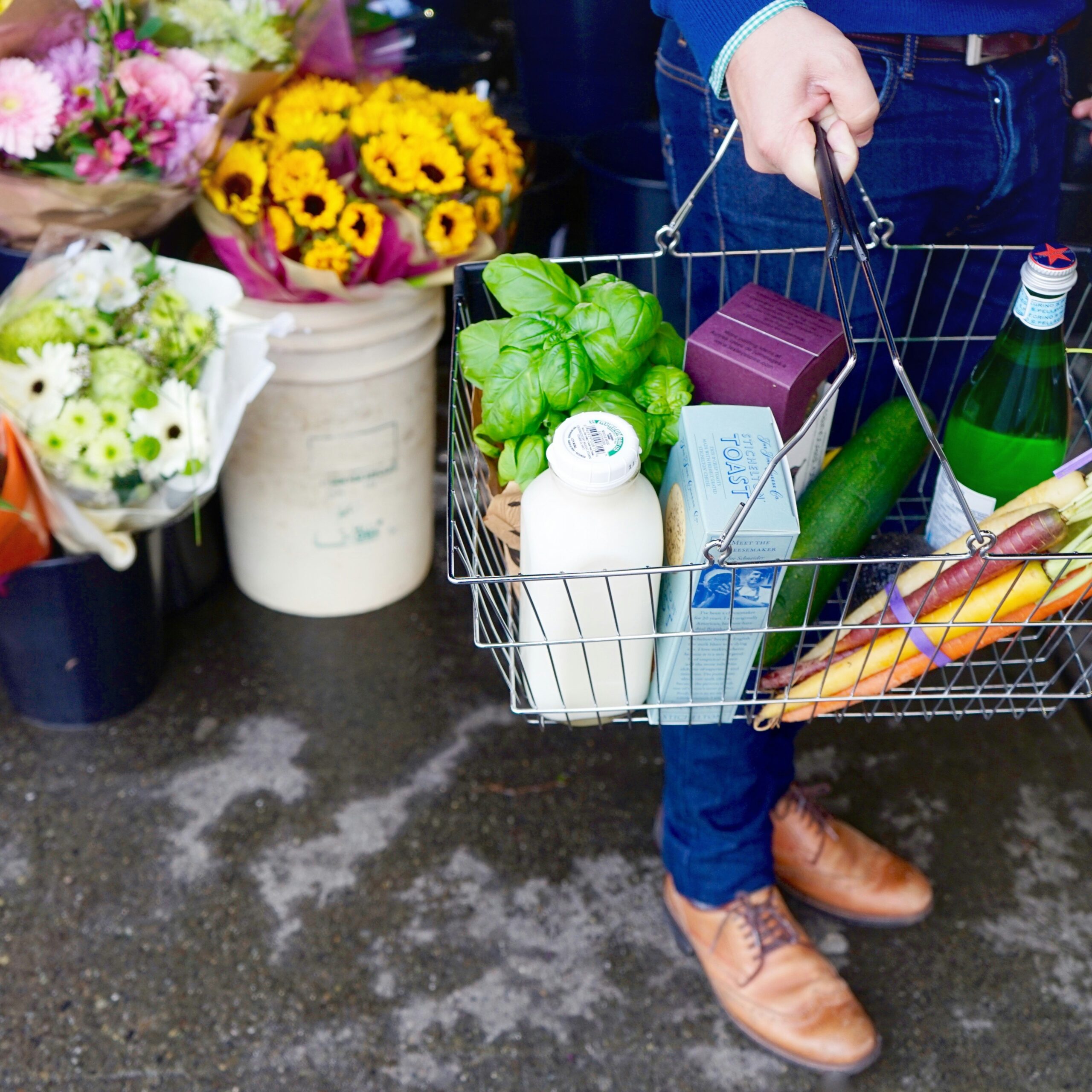 Man in blue jeans holding a basket of groceries
