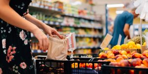 Woman is chooses fruits and vegetables food market. Reusable bag shopping. Zero waste