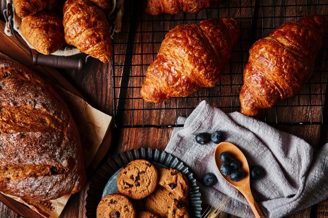 Delicious pastry and wheat spikes on the wooden table frozen baked goods