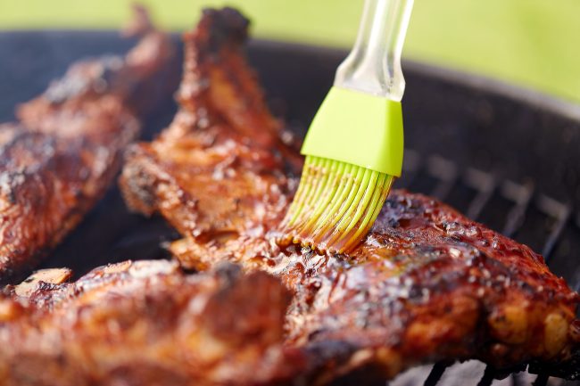 close up of barbecue meat roasting on grill barbecue sauces
