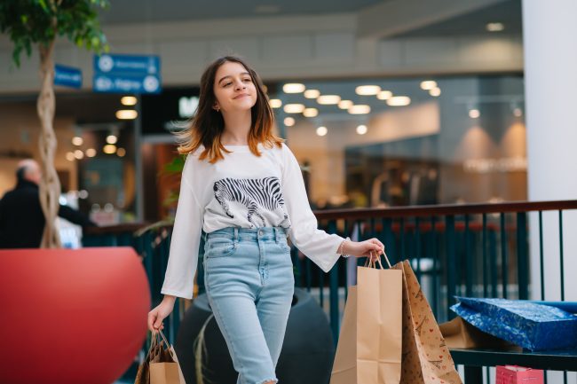 retail, gesture and sale concept – smiling teenage girl with many shopping bags at mall. paying too much