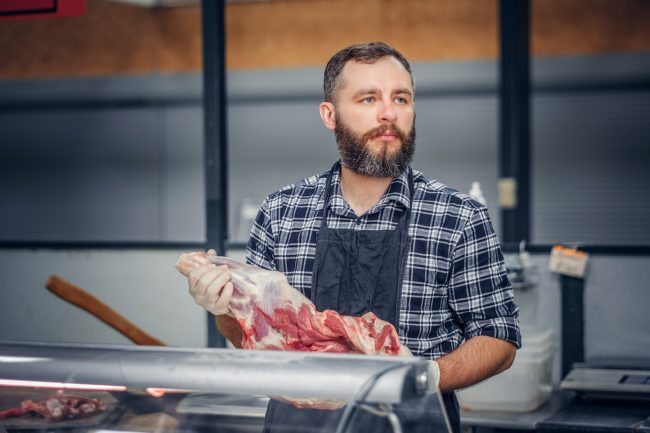 Bearded meat seller serving fresh cut meat. perfect steak