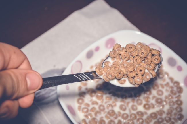 closeup of hand holding corn flakes with milk in a spoon lab tests