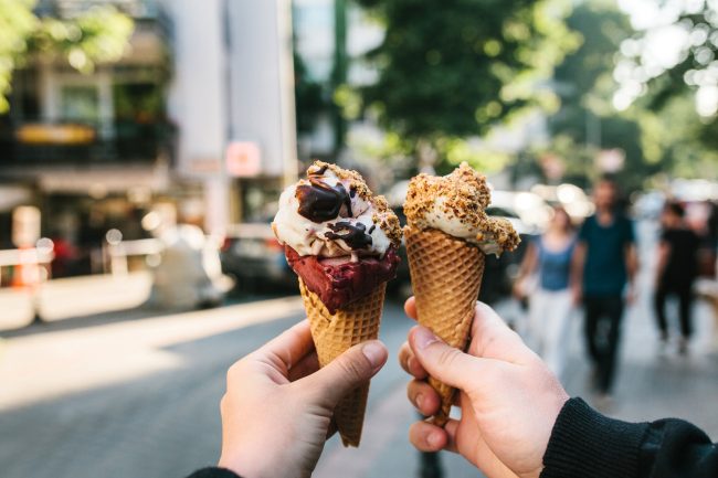 Men’s and women’s hands hold ice cream in the background of the city in summer. Summer time, delicious food, dessert. low fat foods