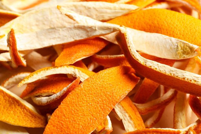 Many dry orange peels on white table, closeup kitchen scraps