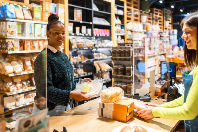 Saleswoman serving customer buying bread in organic supermarket coupon use