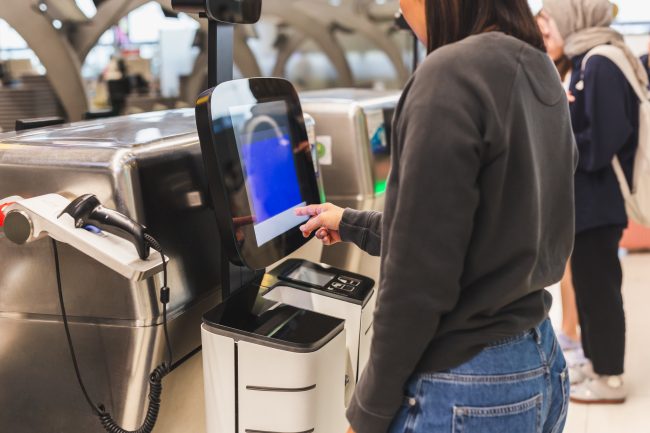 Woman using service machine for self check in at airport. self-checkout scanners