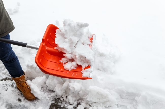 Man with shovel cleaning winter snow. Household Staples Before Winter