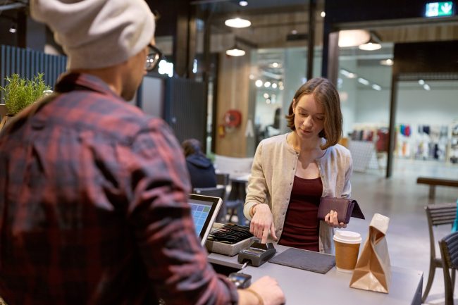 happy woman paying for purchases at cafe impulse buying