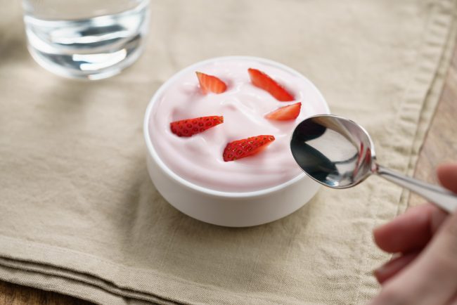 pov teen girl hand eating organic strawberry yogurt healthy grocery items