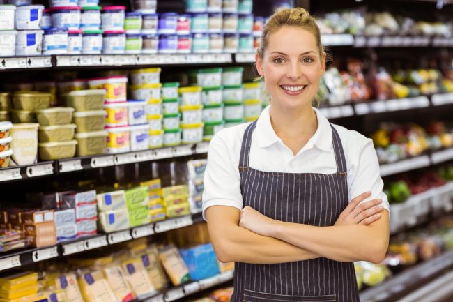 Portrait of a smiling blonde worker with arms crossed in supermarket The Grocery Store Section That’s Packed With Hidden Discounts