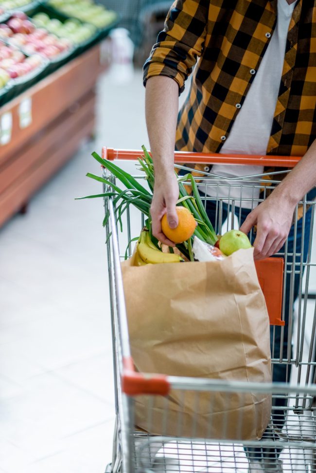 Young handsome man in a supermarket grocery shopping The Scary Reason Some Grocery Stores Rearrange Aisles Overnight