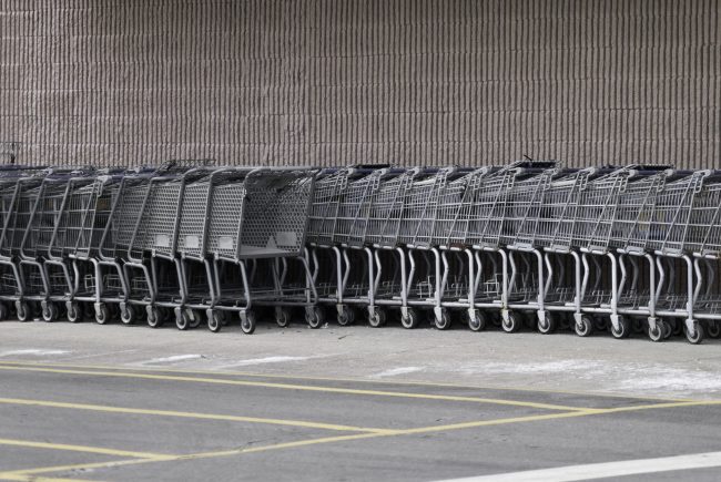 A gathering of grocery carts at the side of a building. How 6 Supermarkets Are Using “Smart Carts” to Change How You Shop