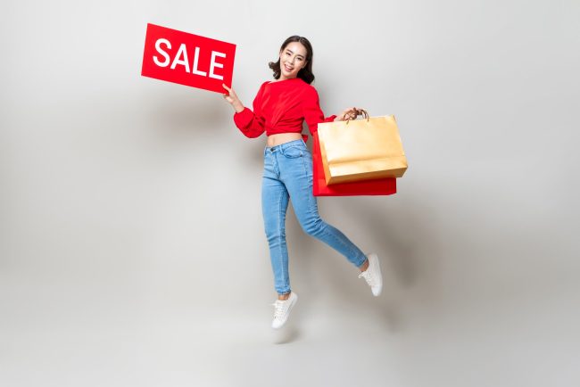 Happy,Asian,Woman,Holding,Shopping,Bags,And,Red,Sale,Sign 10 Sales Events That Beat Black Friday Pricing