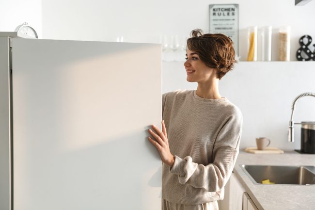 Happy,Young,Woman,Standing,At,The,Opened,Fridge 11 Freezer Hacks That Keep Foods Fresh Longer