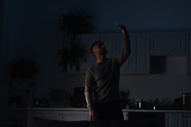 Man,Holding,Smartphone,In,Raised,Hand,While,Searching,For,Connection 8 Grocery Items That Always Sell Out During a Power Outage