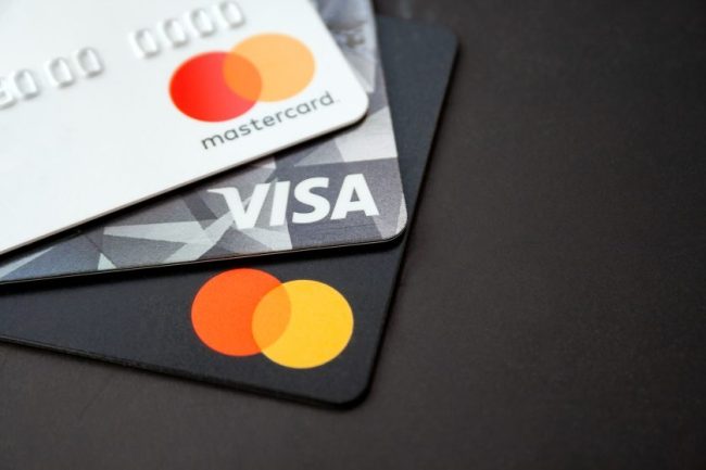 A stack of Visa and Mastercard credit cards resting on a black surface. Consumers Are Leaning on Credit Cards as Prices Rise: 7 Ways to Avoid Turning Groceries Into Long-Term Debt