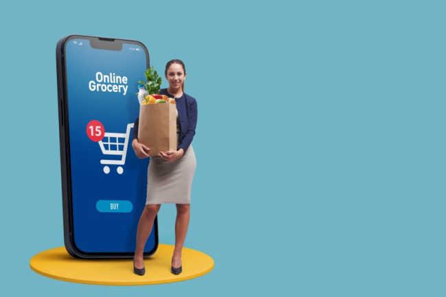 A woman holding a paper grocery bag next to a giant smartphone displaying an online grocery app. Grocery Costs That Make Online Ordering More Expensive Than Pickup