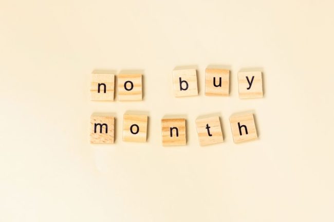 Wooden letter tiles spelling out no buy month on a beige background. The 'No-Spend Weekend' Trend Is Growing: Families Say It's Helping Them Save Without Feeling Deprived