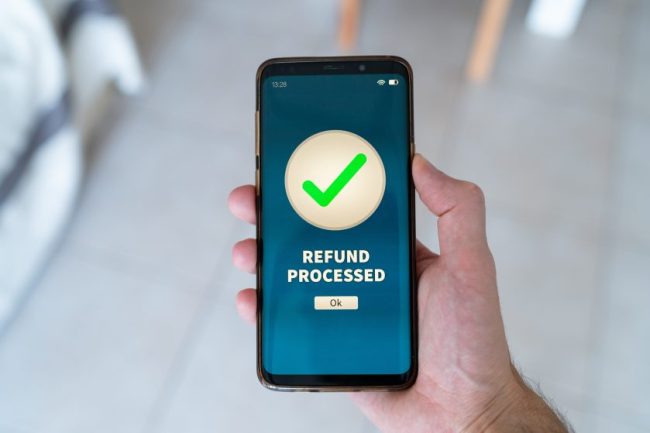 A hand holding a smartphone showing a refund processed screen. Why Grocery Refund Credits Deserve the Same Attention as Cash Refunds