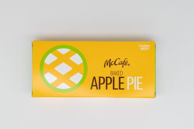 A yellow McDonald’s McCafé Baked Apple Pie box resting on a white background. McDonald’s Apple Pie Has Changed More Than You Think — Here’s the Story