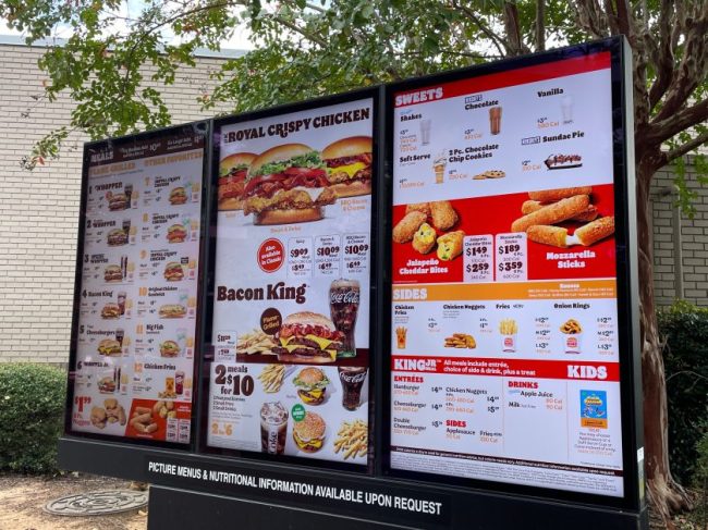 A illuminated fast-food drive-thru menu board displaying burgers, chicken, sides, and prices. Fast-Food Prices Changed at Thousands of Restaurants This Week — Here’s What Got More Expensive