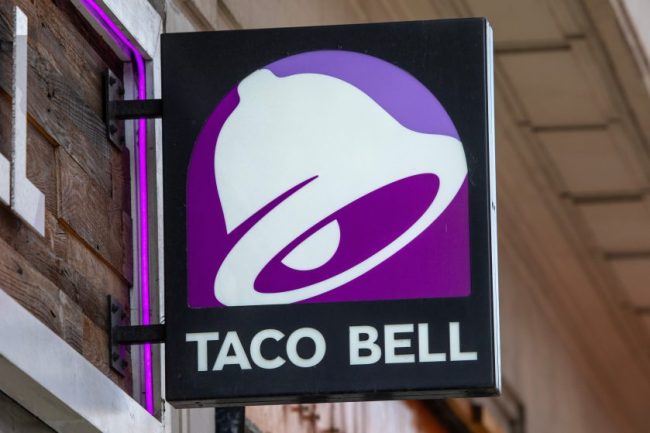 A purple and white Taco Bell logo sign mounted outdoors. Taco Bell Just Brought Back Its Answer to the Choco Taco — But It Costs $3.99