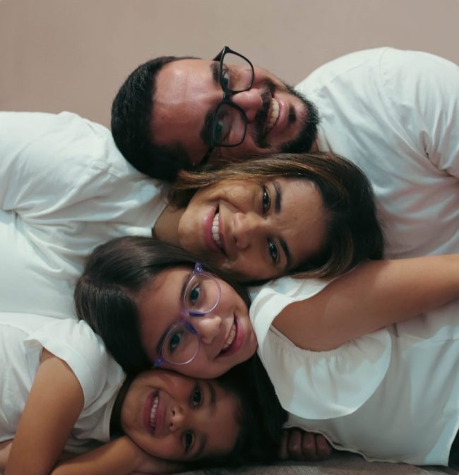 A family of four smiling and lying stacked together while wearing white shirts. Ordering Fast Food for a Family of 4? These 7 Mistakes Can Add $20 to the Bill