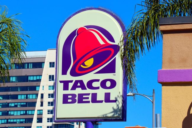 The illuminated outdoor sign of a Taco Bell restaurant against a clear blue sky. 8 Taco Bell Ordering Tricks Regular Customers Swear By