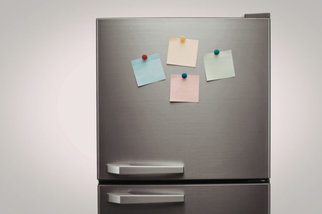 The front of a stainless steel refrigerator decorated with colorful sticky notes held by magnets. 8 Foods You Should Stop Storing in Your Refrigerator Door