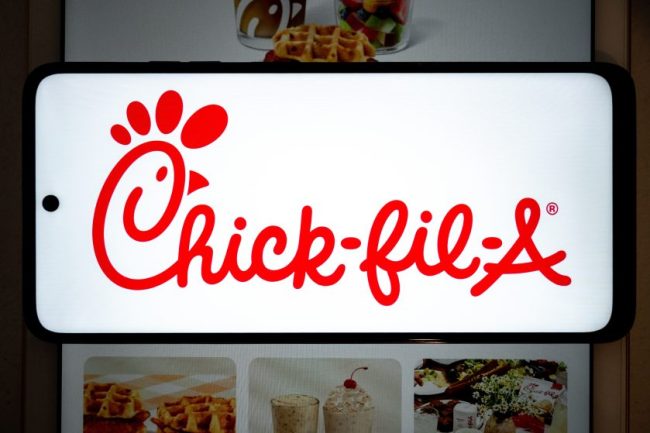 The red Chick-fil-A logo displayed brightly on a smartphone screen. 10 Chick-fil-A Hacks That Can Get You More From Your Next Order
